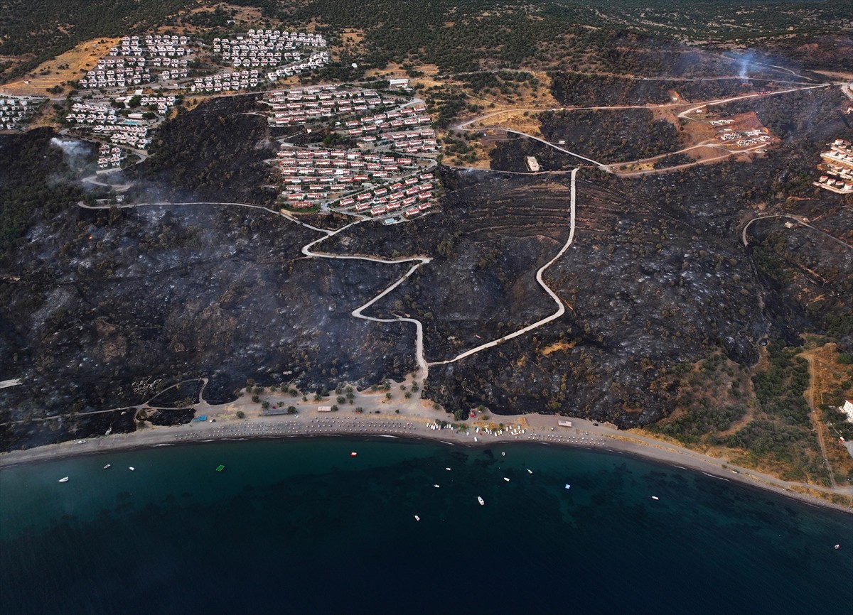 İzmir'in Dikili ilçesinde ormanlık alanda başlayan ve yerleşim yerlerine yaklaşan yangına havadan...