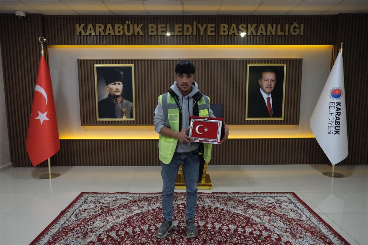 Karabük'te temizlik işçisinin, çöpten bulduğu Türk bayrağını yerden alarak bahçe duvarına asması...