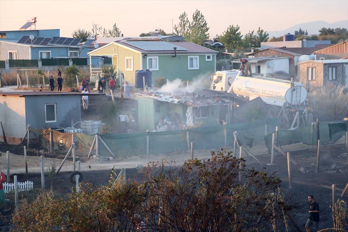 İzmir'in Menderes ilçesinde otluk alanda çıkan yangın 8 evde hasar oluşmasına neden oldu.