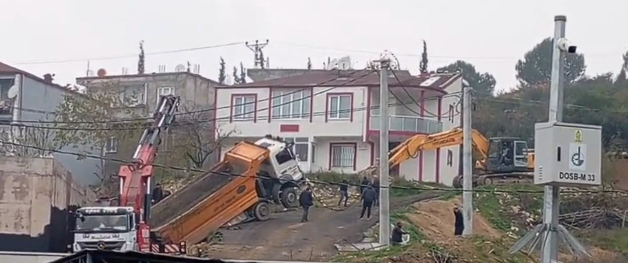 KOCAELİ'NİN DİLOVASI İLÇESİNDE HAFRİYAT DÖKÜMÜ SIRASINDA GERİ KAYARAK ASKIDA KALAN KAMYON, VİNÇ VE...